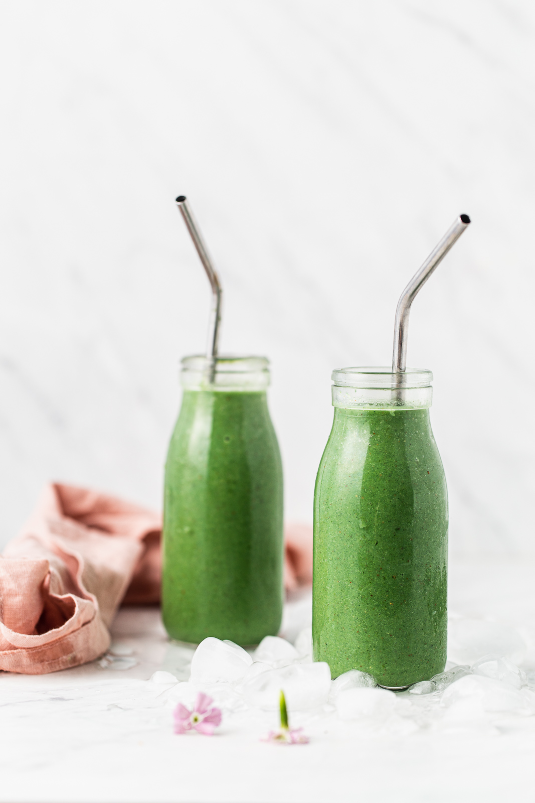 two green smoothies in glasses with straws photography