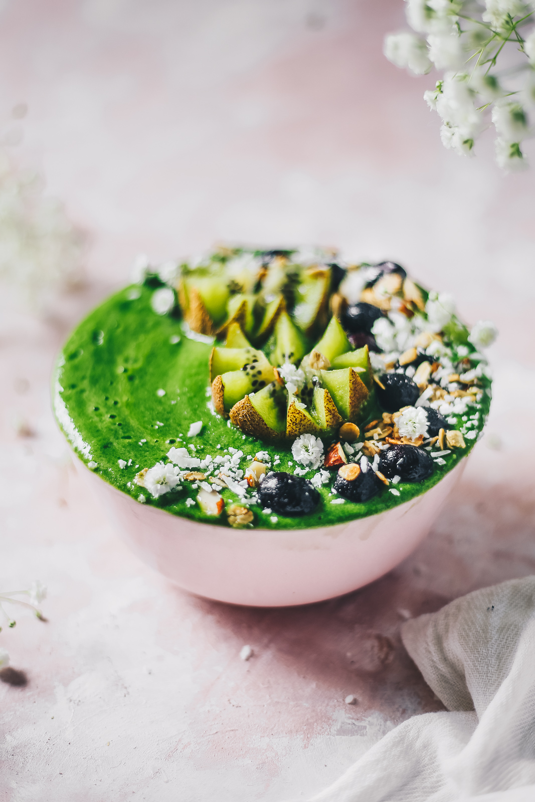 green smoothie bowl topped with kiwi blueberries and flowers photography
