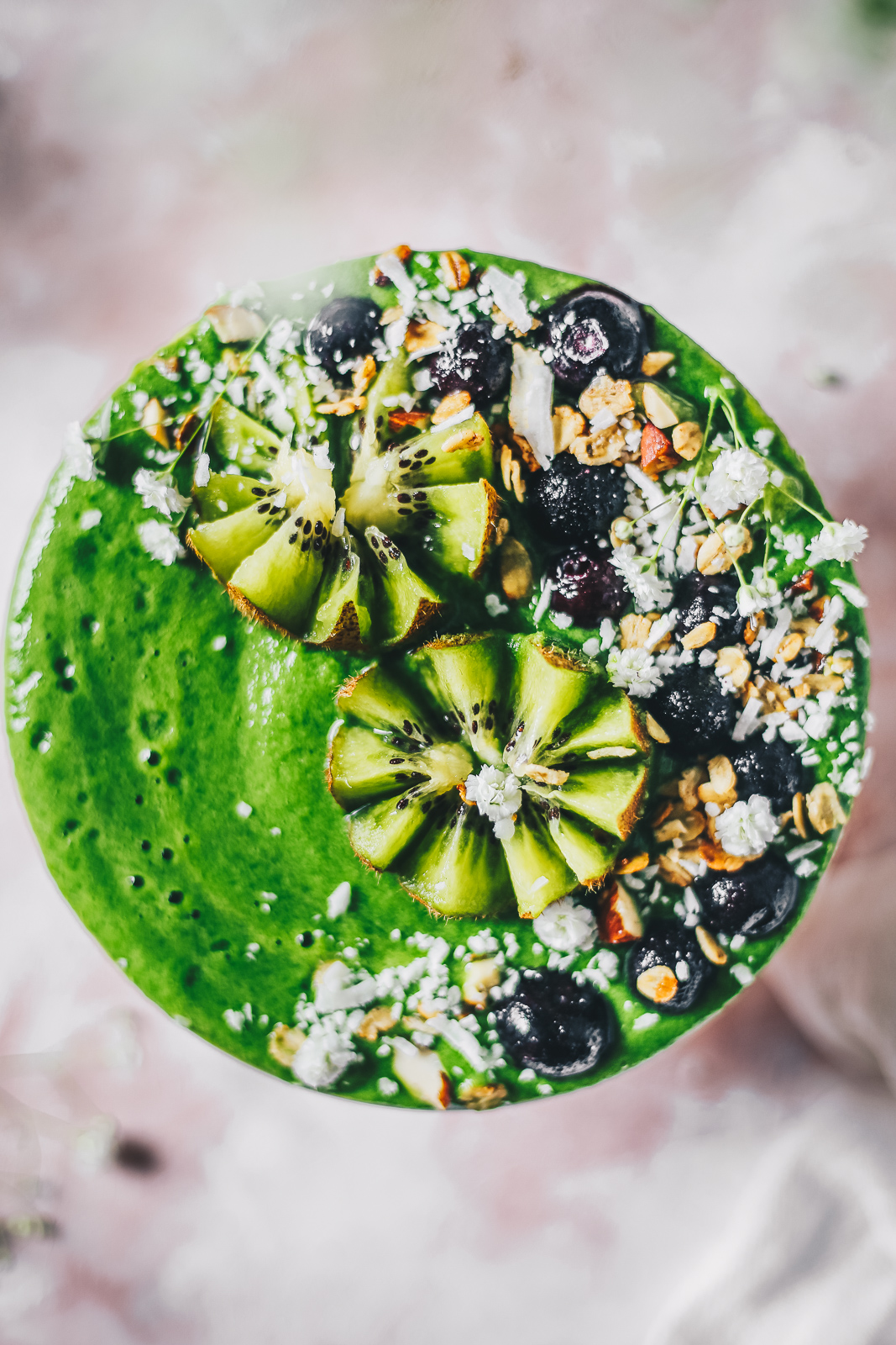 green smoothie bowl topped with kiwi blueberries and flowers