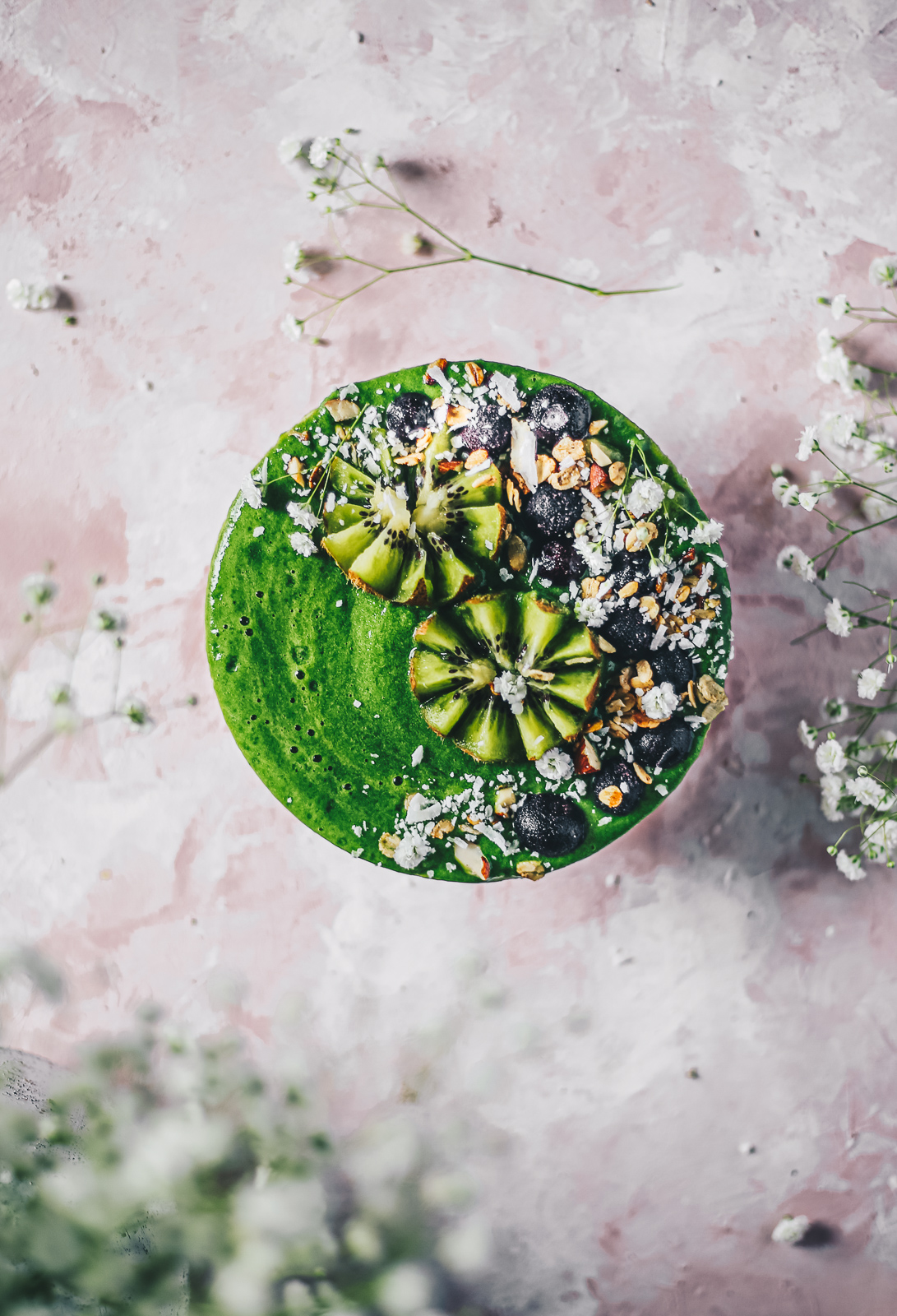 green smoothie bowl topped with kiwi blueberries and flowers