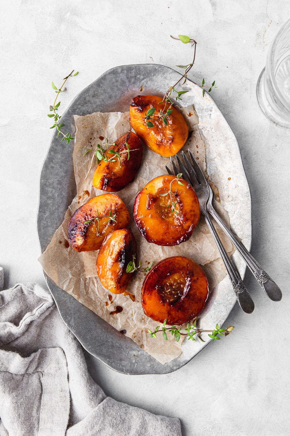 caramelized peaches on a platter with fresh thyme