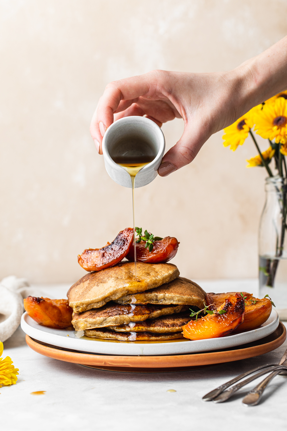 pancakes topped with caramelized peaches and pour of maple syrup food photography