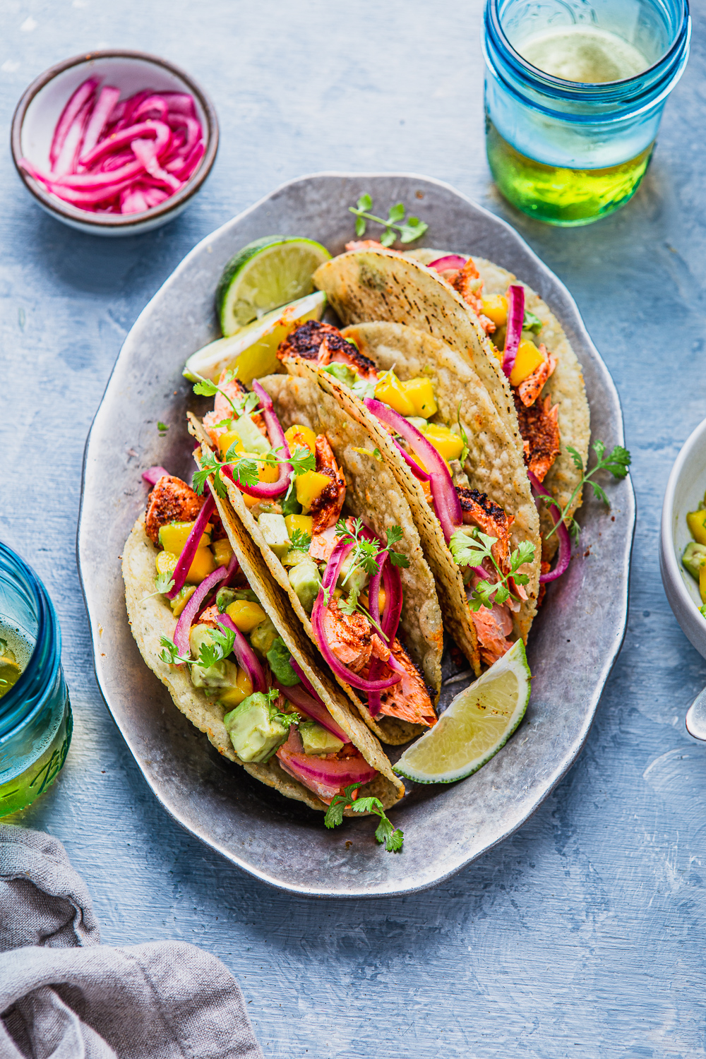 fish tacos with avocado and mango salsa pickled onions on a tray photography with beer