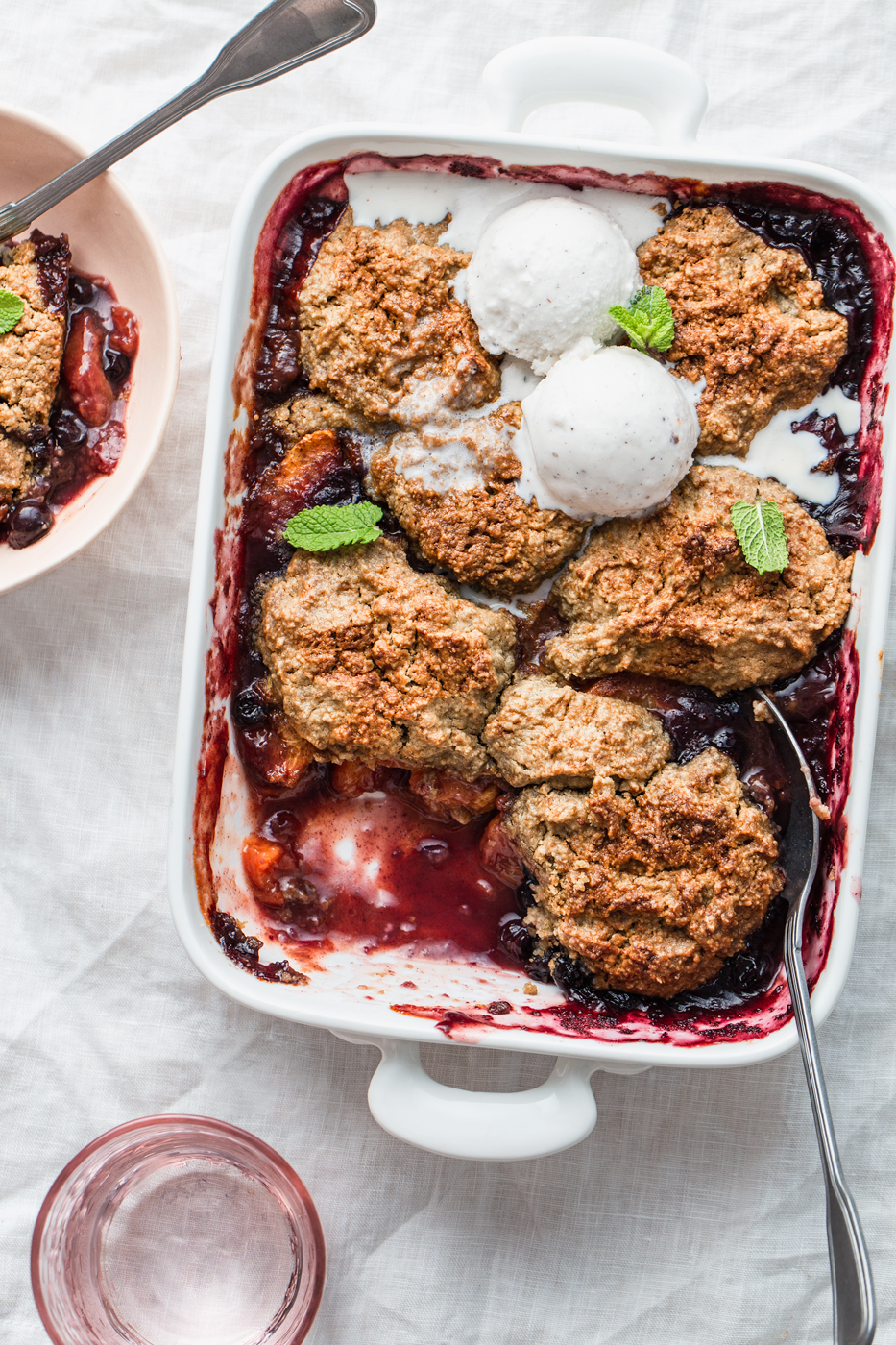 blueberry peach cobbler in a baking dish with ice cream food photography