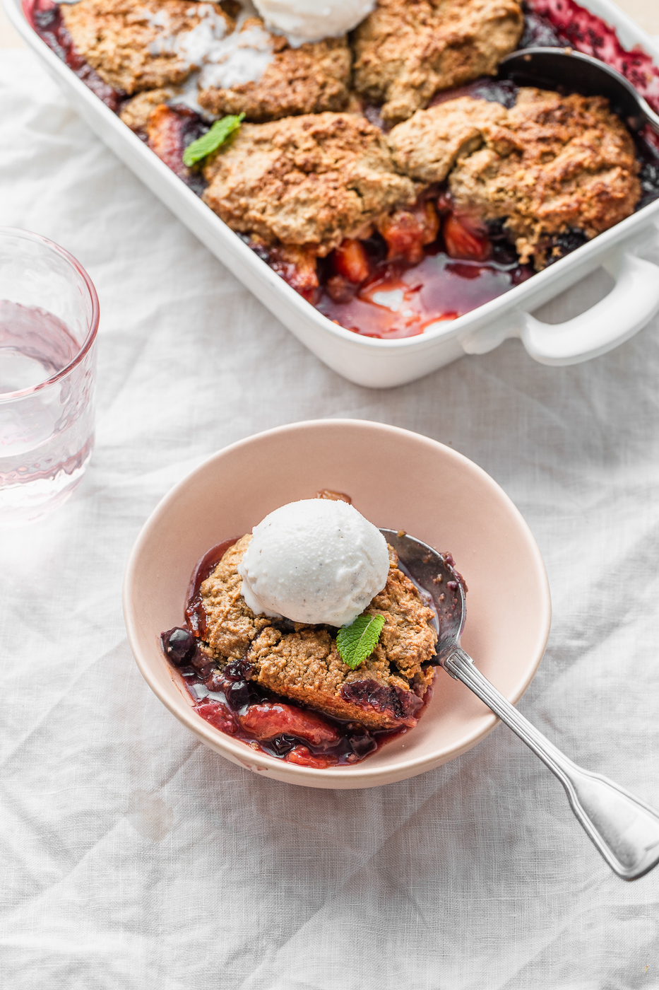 peach blueberry cobbler in a bowl with ice cream