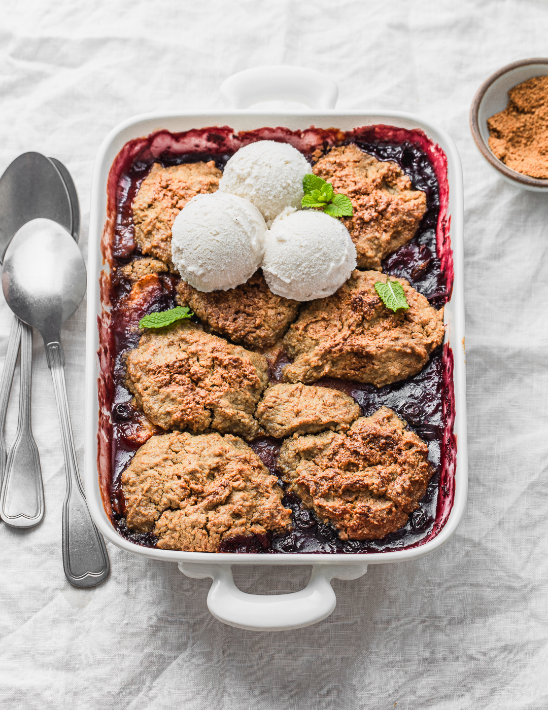 peach and blueberry cobbler with ice cream in a baking dish