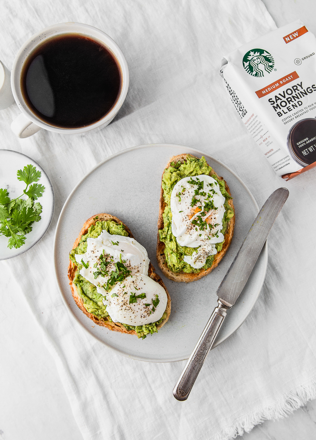 mashed avocado and poached eggs toasts on a plate with a cup of starbucks coffee photography