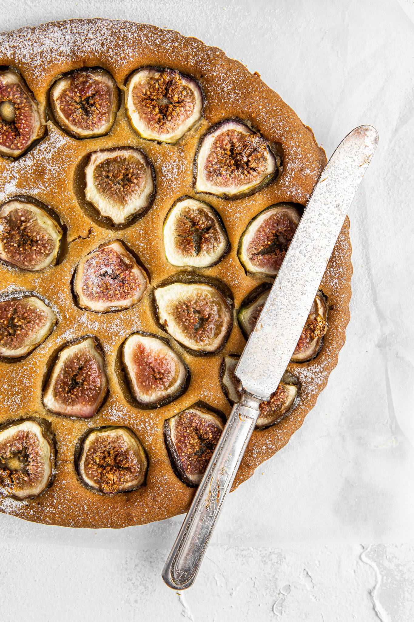 cake with figs and powder sugar and cake knife food photography