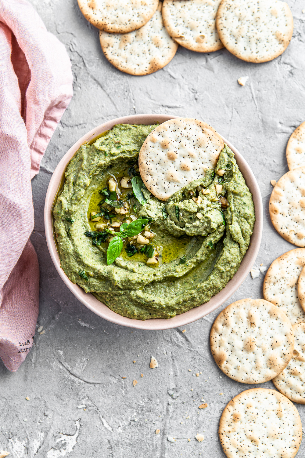 green dip in a pink bowl with crackers food photography