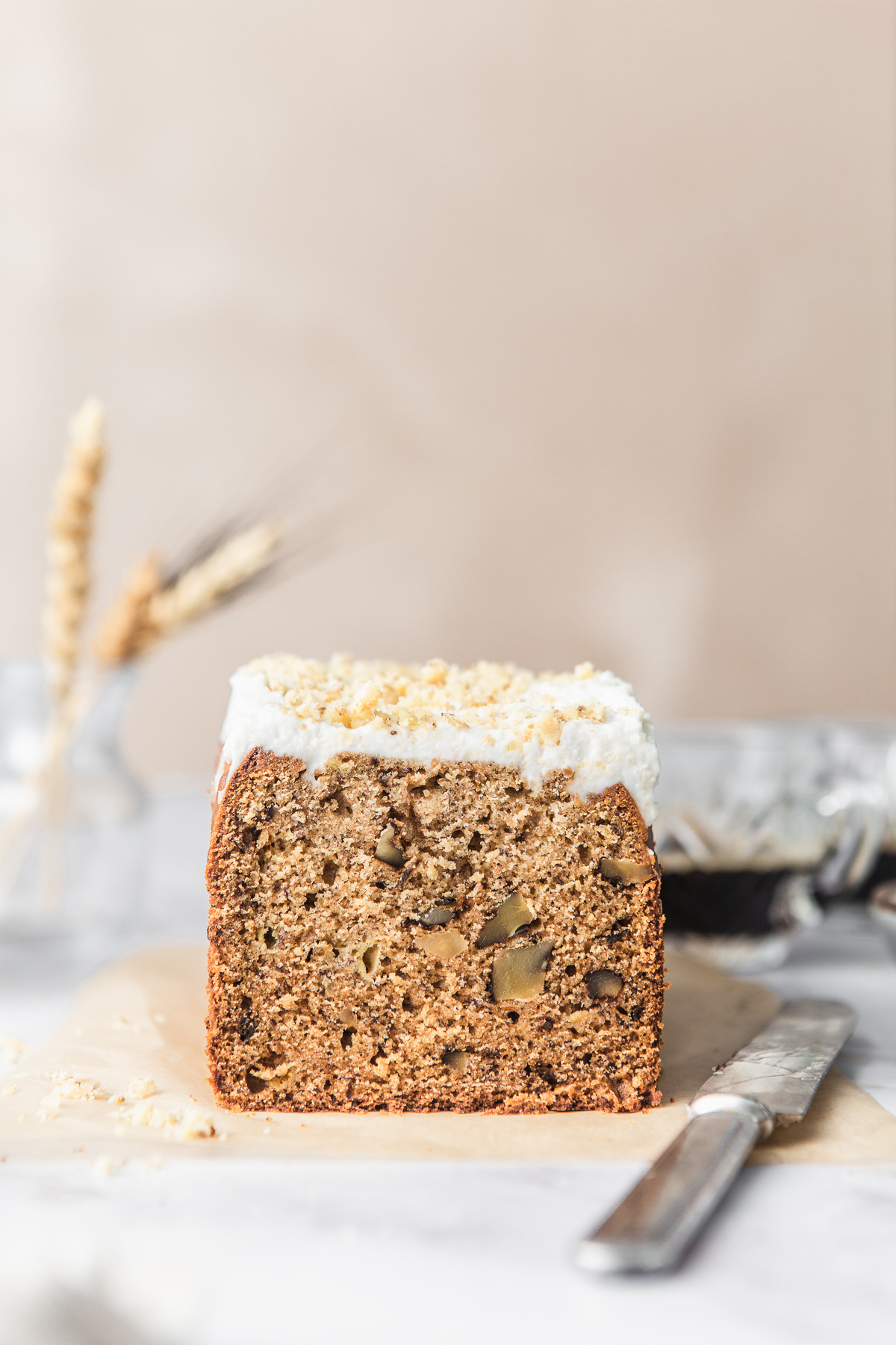 walnut banana bread loaf with and cashew frosting with knife and espresso