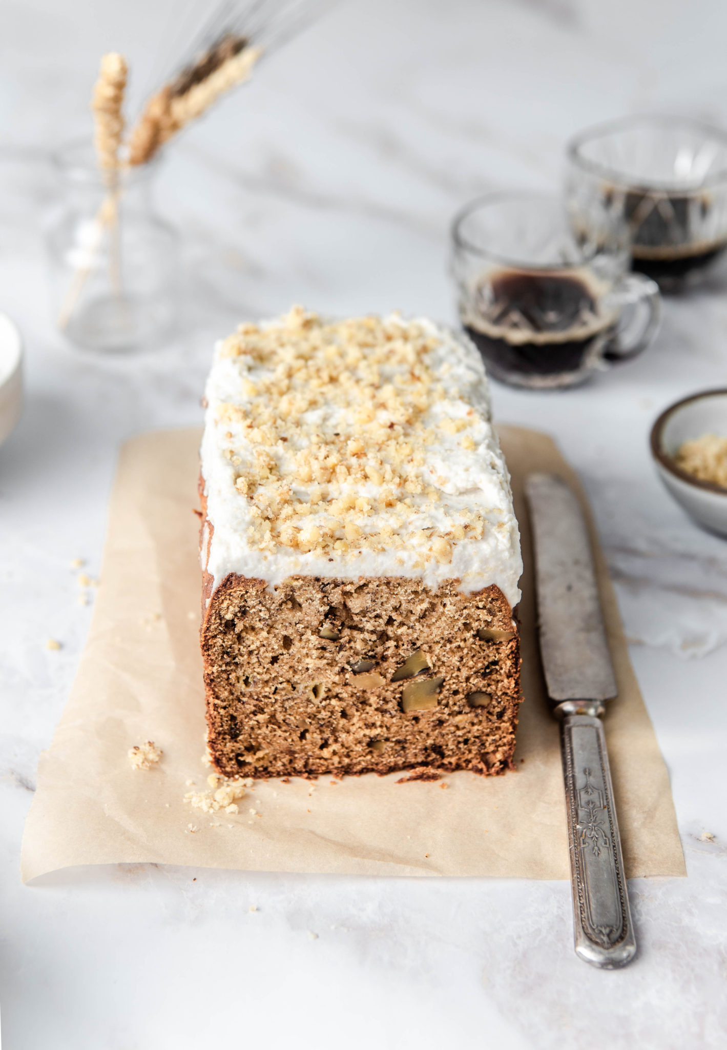 banana bread loaf with walnuts and cashew frosting with knife and espresso photography