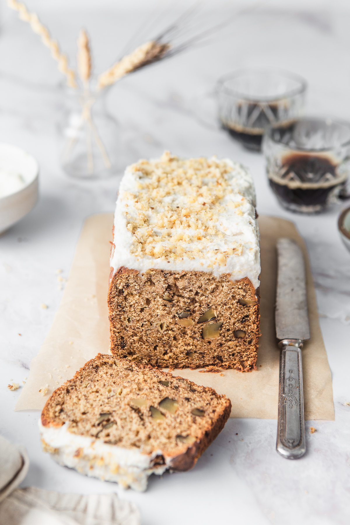 banana bread loaf with walnuts and cashew frosting with knife and espresso