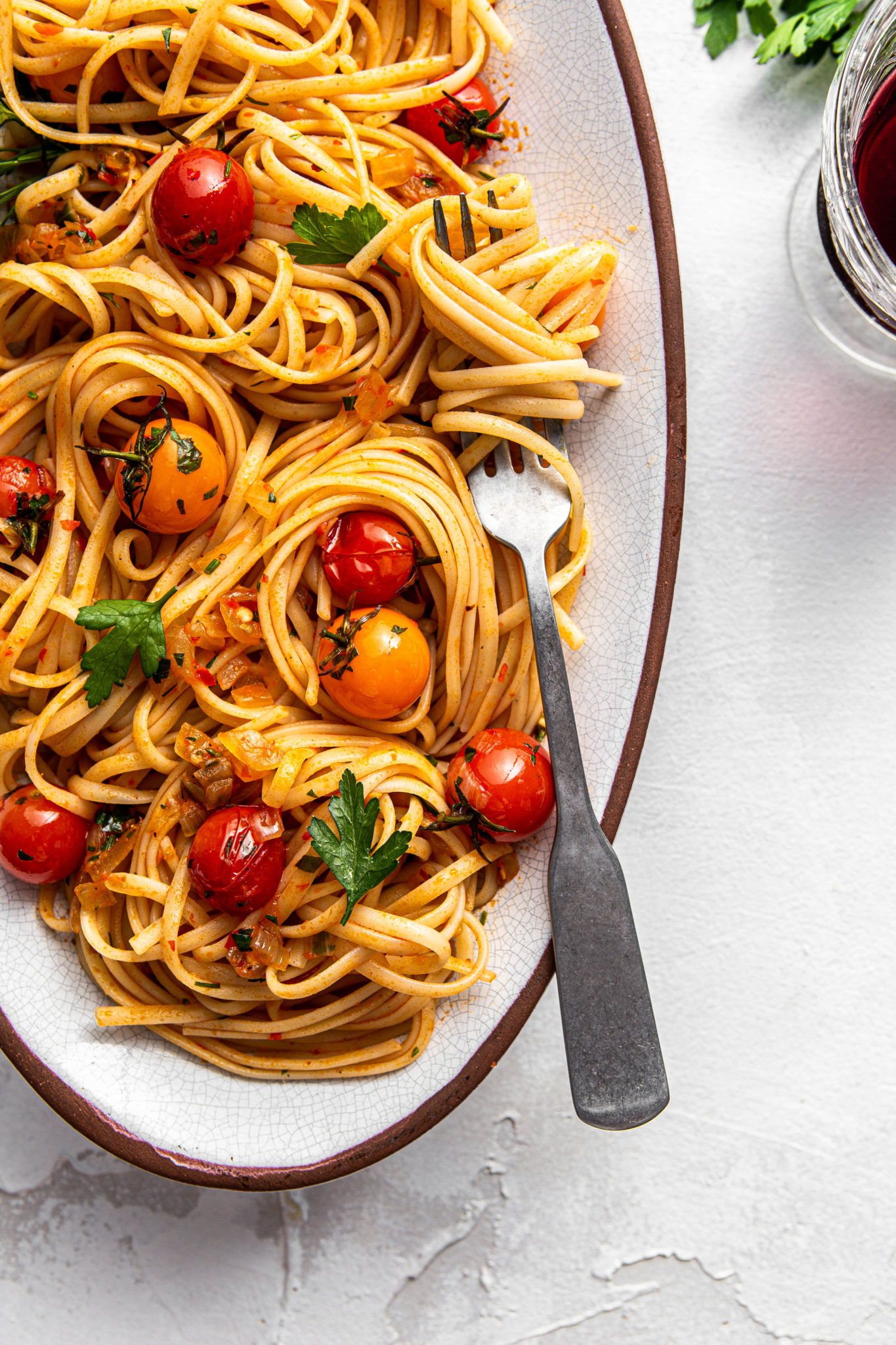 fettuccine noodles with harissa and cherry tomatoes parsley and red wine glass