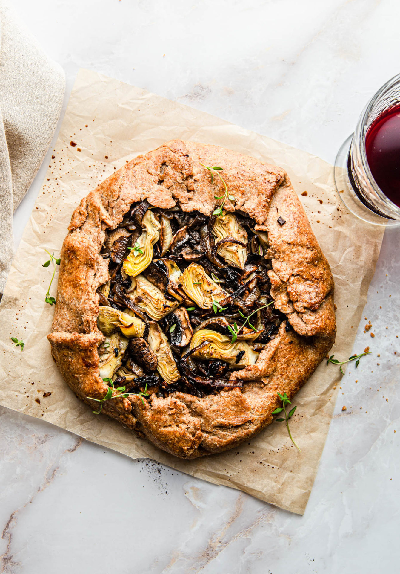 rustic galette with mushrooms onions and artichokes with glass of red wine