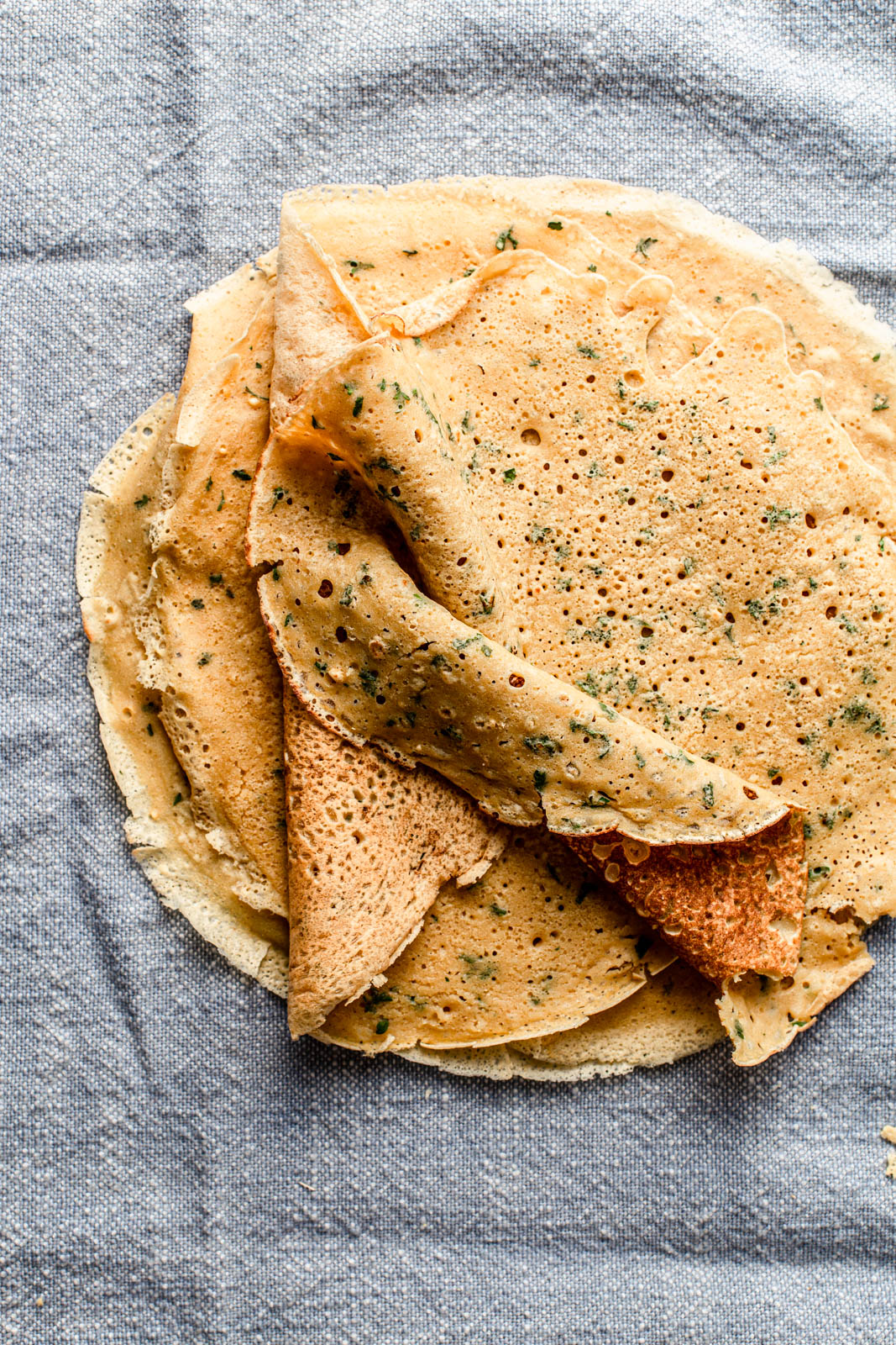 chickpea pancakes with herbs on a blue towel food photography