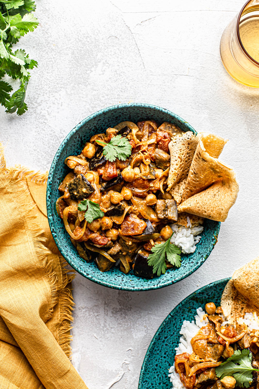 Roasted Eggplant Curry bowl with chickpeas cilantro and chickpea pancake in a blue bowl food photography