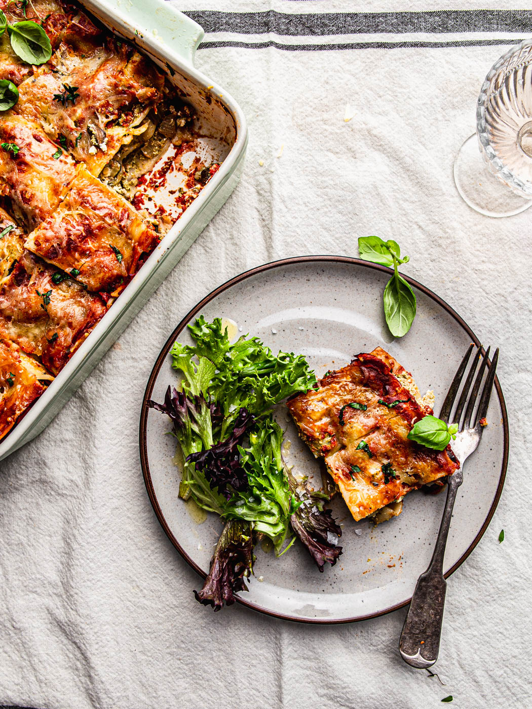 piece of lasagna on a plate with a side salad food photography food styling