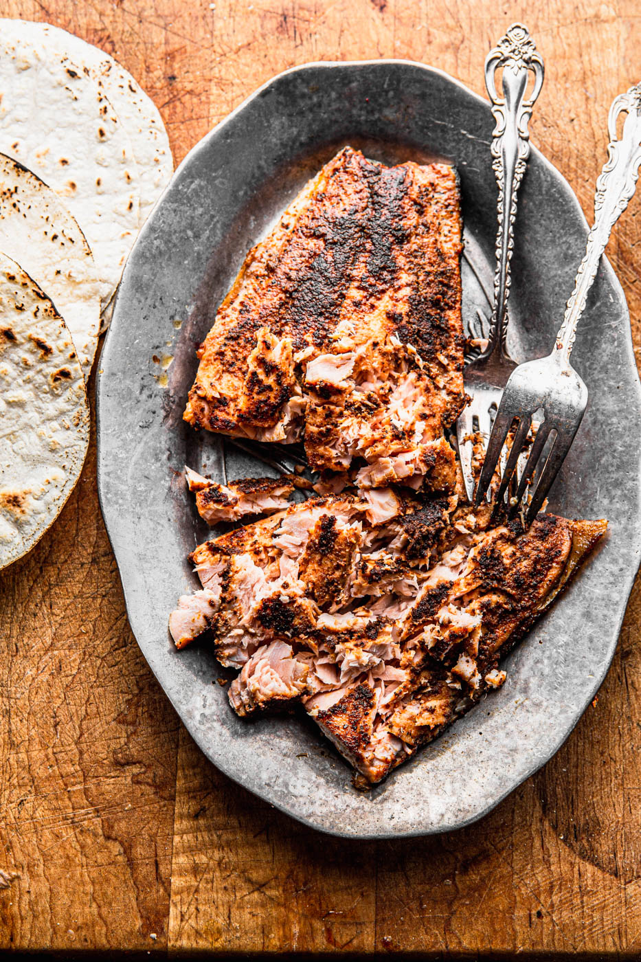 blackened seared salmon on a wooden board and silver platter with tortillas food photography