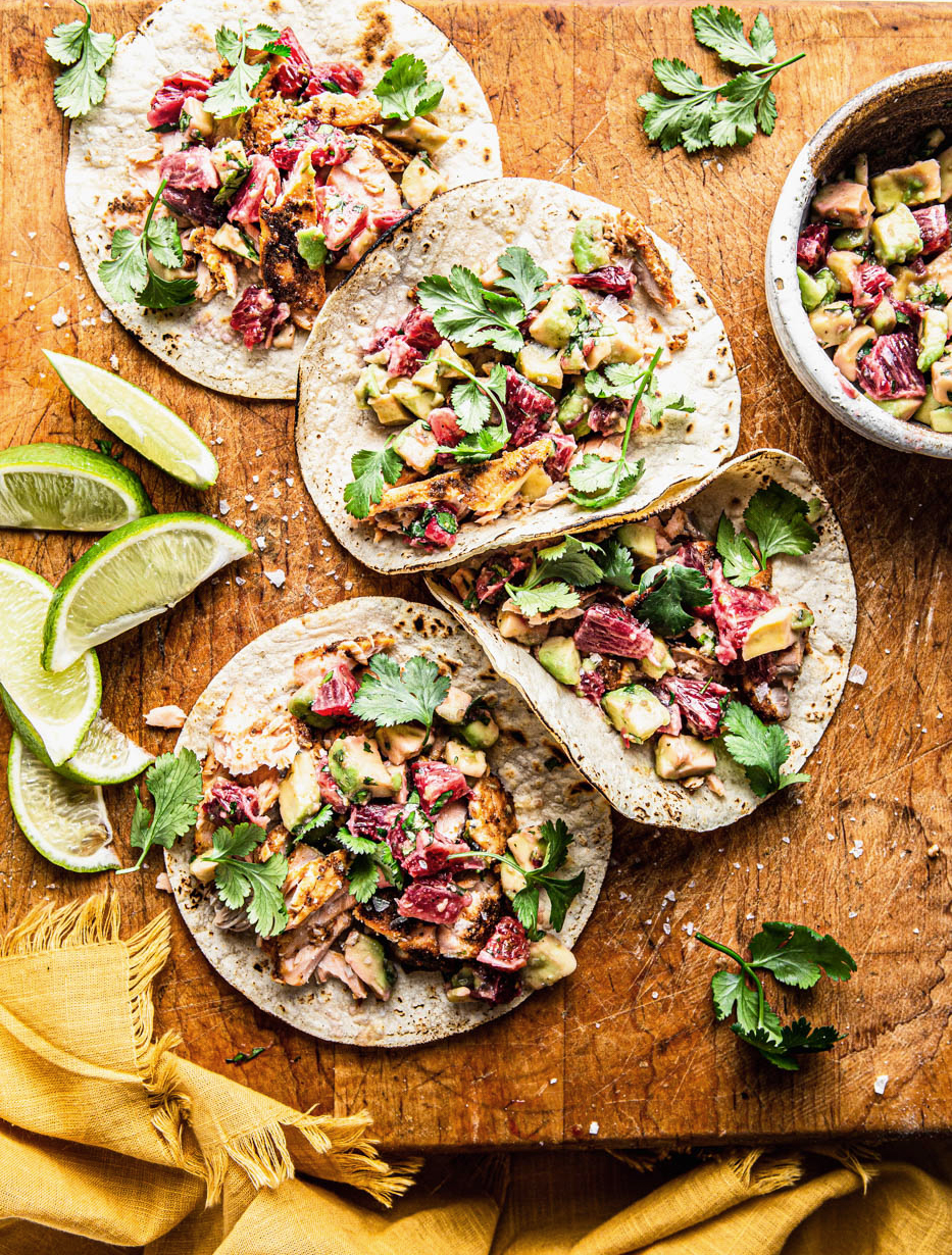 salmon tacos with salsa on a wooden board with lime wedges food photography food styling