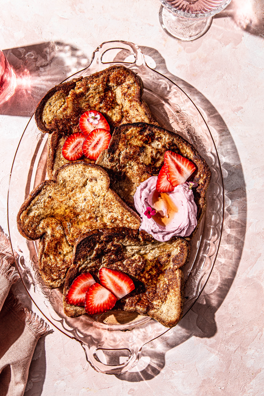 Dairy-Free French Toast with cream and Strawberries on a pink glass platter hard light food photography