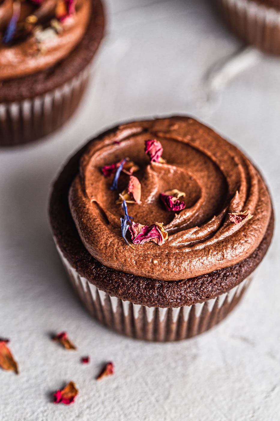 Keto Chocolate Cupcakes with shiny chocolate frosting with rose petals